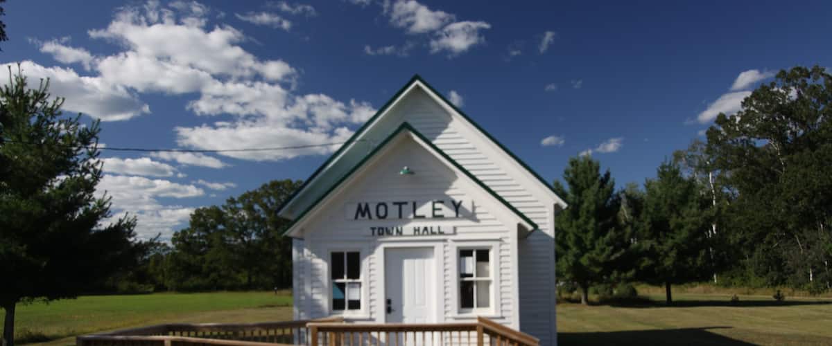 A white building labeled "MOTLEY TOWN HALL" with a wooden deck in front.
