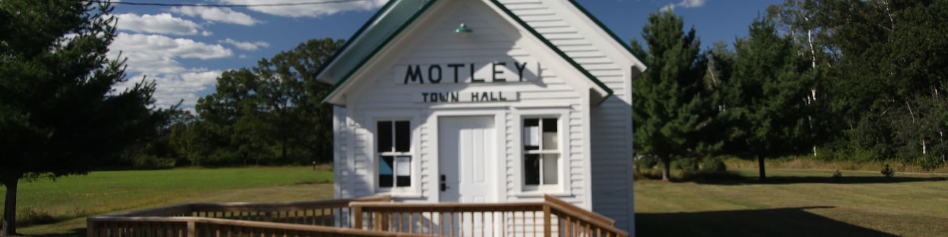 A white building labeled "MOTLEY TOWN HALL" with a wooden deck in front.