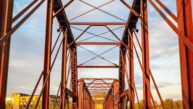 A wooden pedestrian bridge with a metal truss structure.