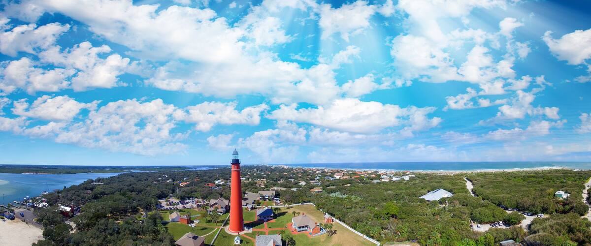 A coastal town with a prominent red lighthouse, a marina, and a mix of residential and commercial buildings.