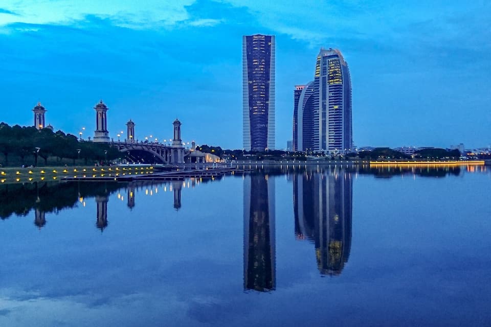 Un horizonte urbano con modernos rascacielos y una masa de agua tranquila que refleja los edificios.