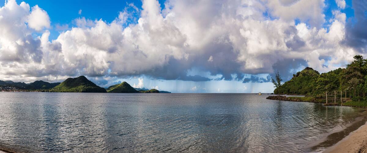 Un lac paisible, avec des montagnes en arrière-plan et un ciel nuageux.