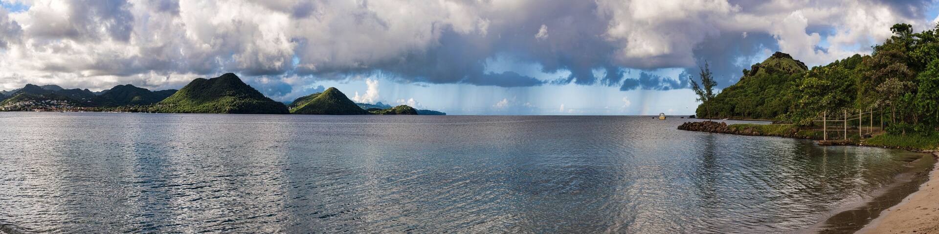 A calm lake with mountains in the background and a cloudy sky.