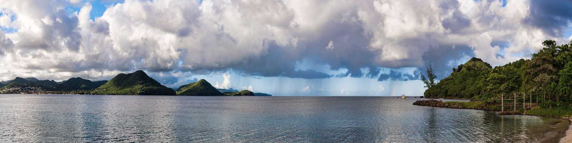 A calm lake with mountains in the background and a cloudy sky.