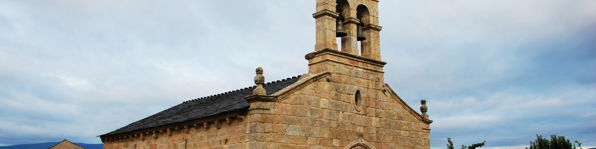 Una iglesia de piedra histórica con un campanario y arcos de entrada.