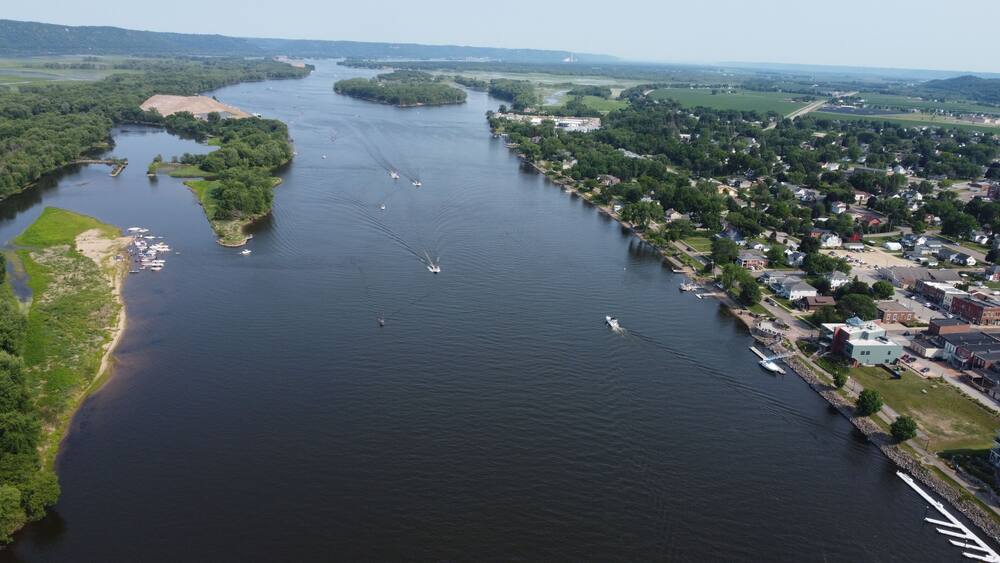 A river with boats, surrounded by greenery and a small town.