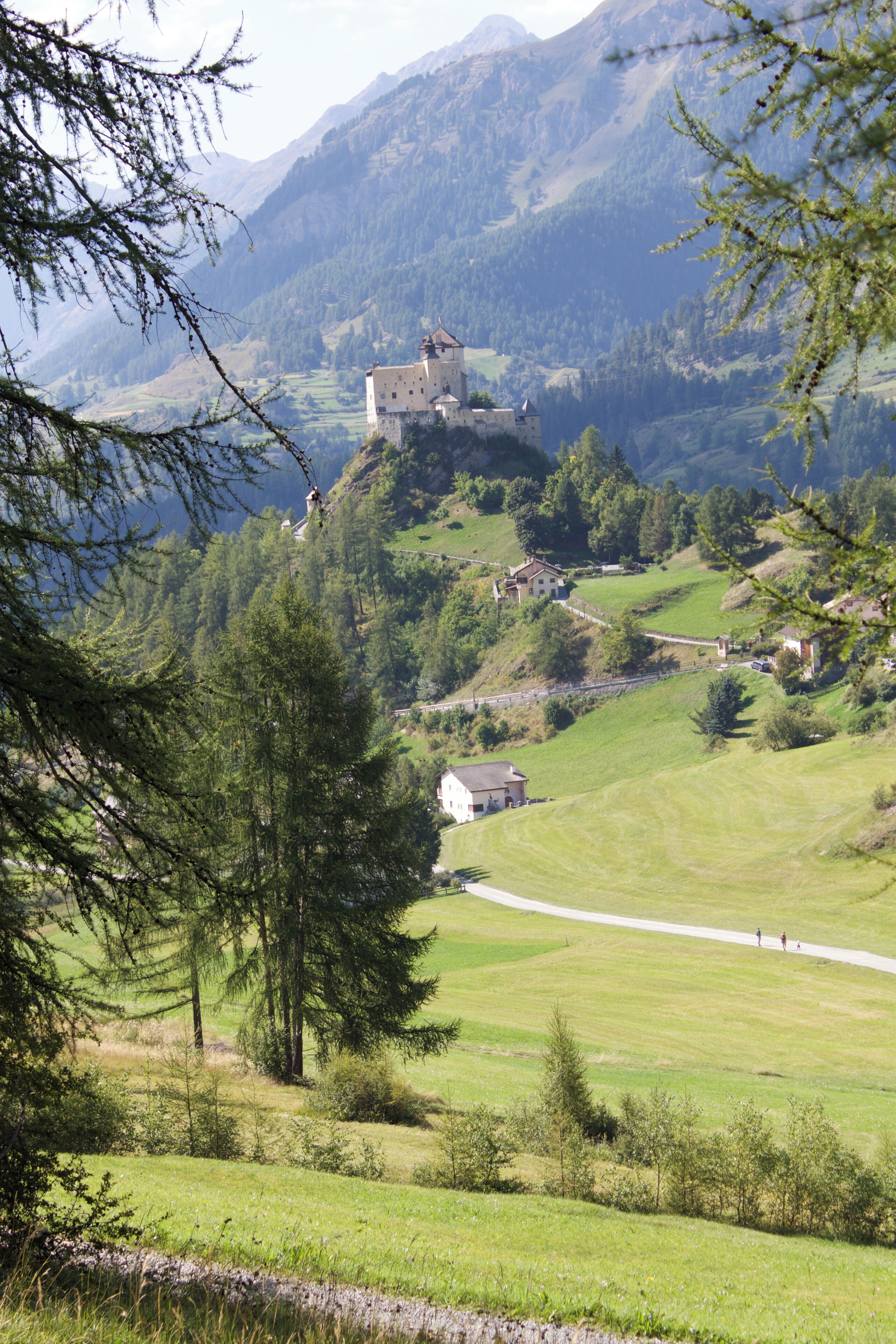 A castle on a hill surrounded by lush green fields and mountains.