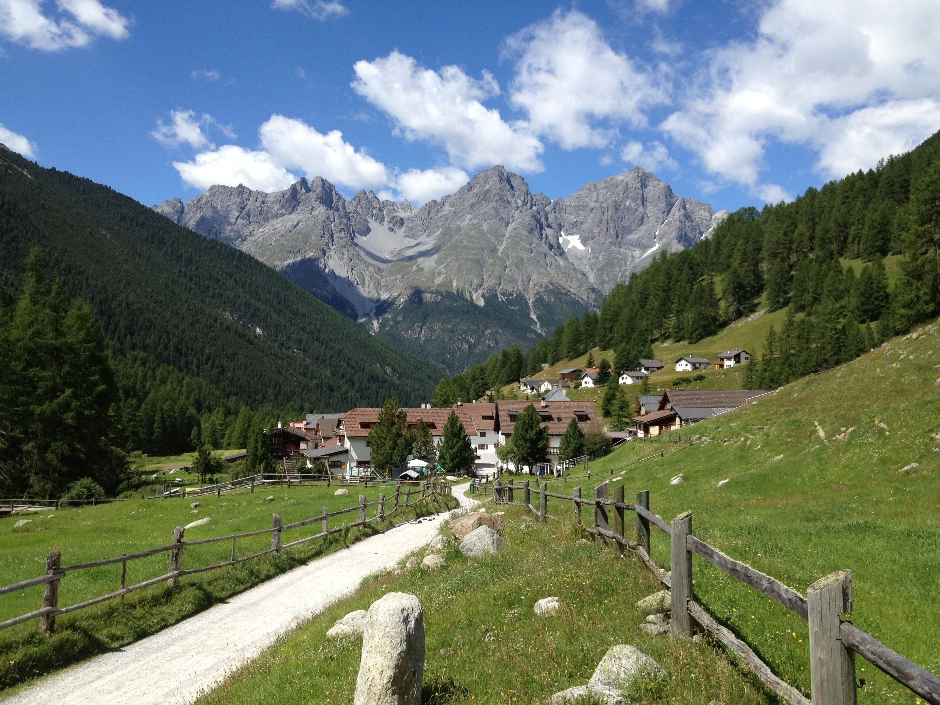 A mountain village with houses and a wooden fence.
