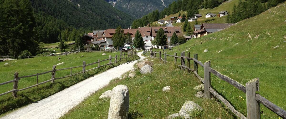 A mountain village with houses and a wooden fence.