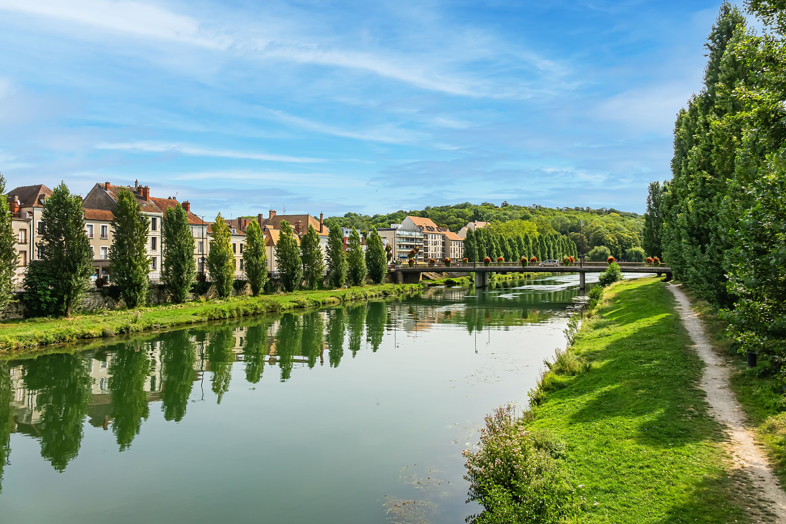 A calm river with buildings and trees along the banks.