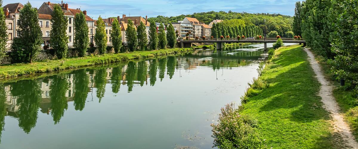 A calm river with buildings and trees along the banks.