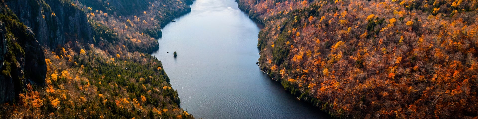 A river valley with autumn foliage, surrounded by forested mountains.
