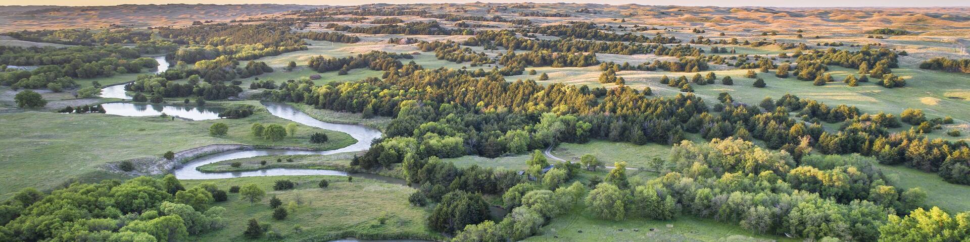 A river winding through a lush landscape with dense forests and open fields.
