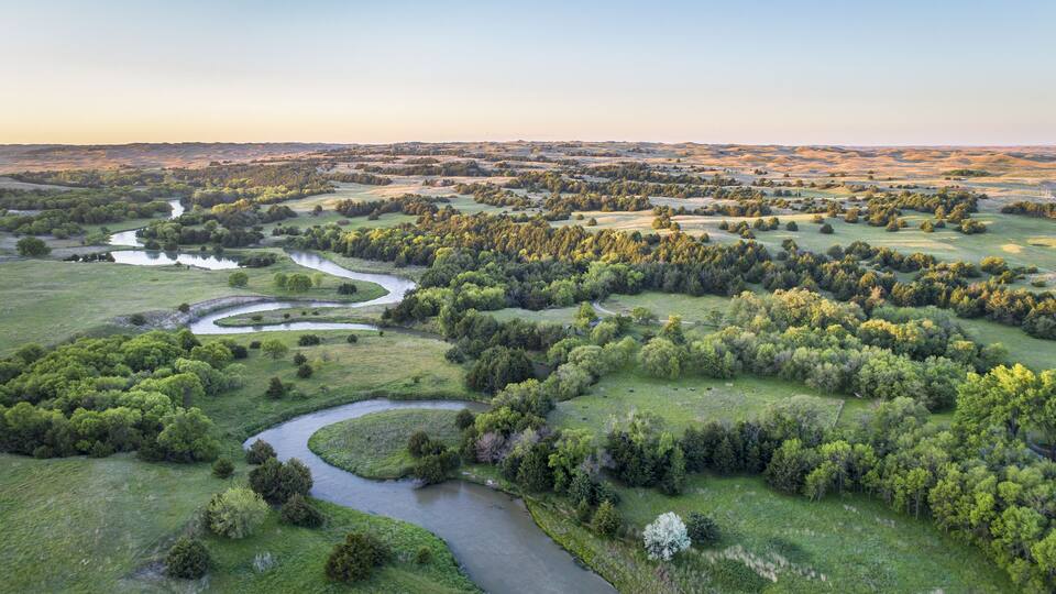 A river winding through a lush landscape with dense forests and open fields.
