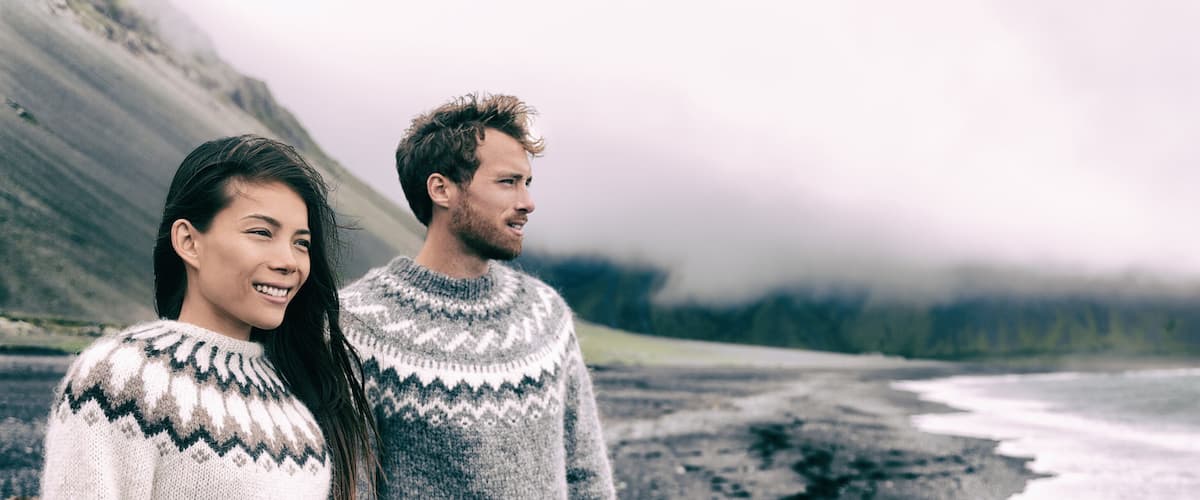 A couple standing on a beach with a glacier in the background.