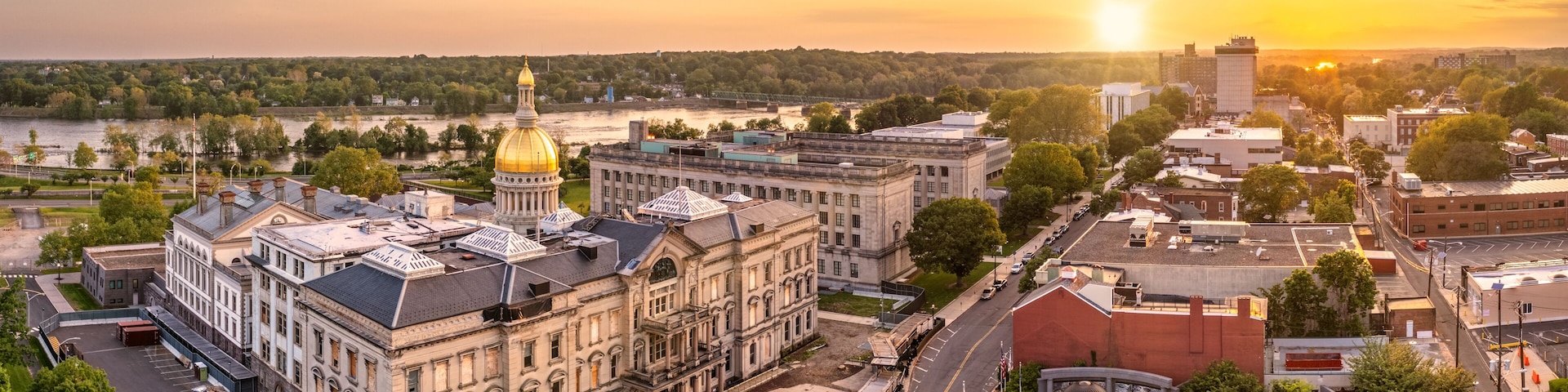 A cityscape with a prominent building featuring a golden dome, surrounded by other historic architecture and a river in the background.