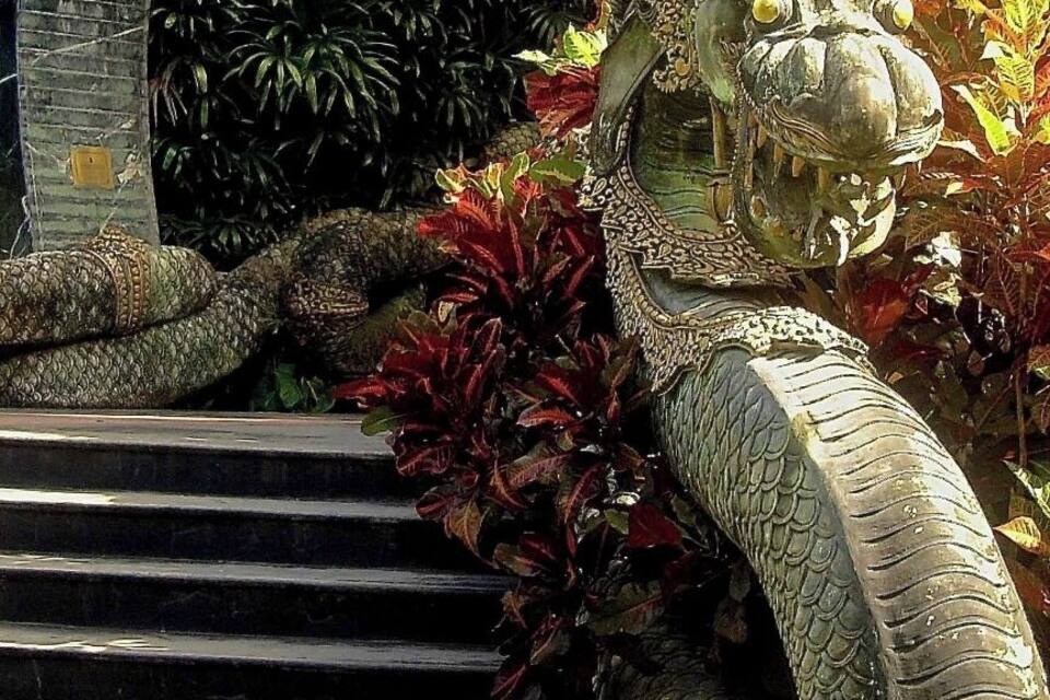 A large, ornate sculpture of a mythical creature with a long neck and scales, positioned on a set of stairs.