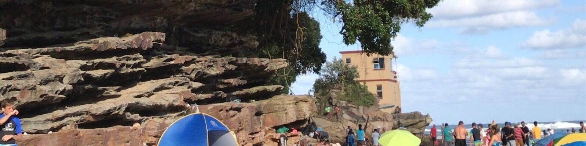 Cliff face of a natural tropical beach cove where sunbathers seek refuge from the hot African sun.