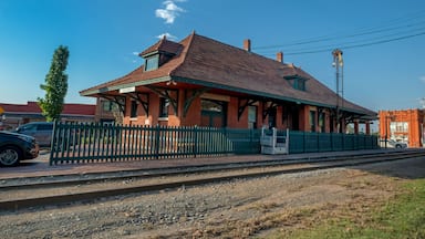Een klassiek treinstation met een rood dak, een groen hek en een helderblauwe lucht.