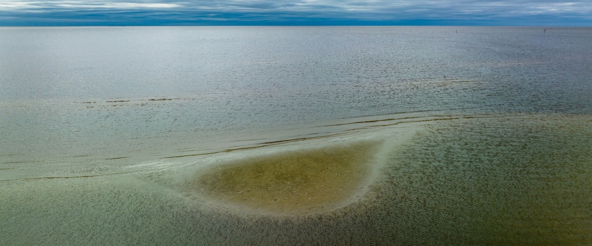 A vast body of water with a sandy beach and a cloudy sky.
