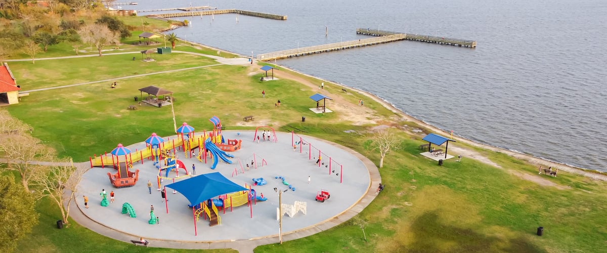 A playground with slides and swings by a lake.