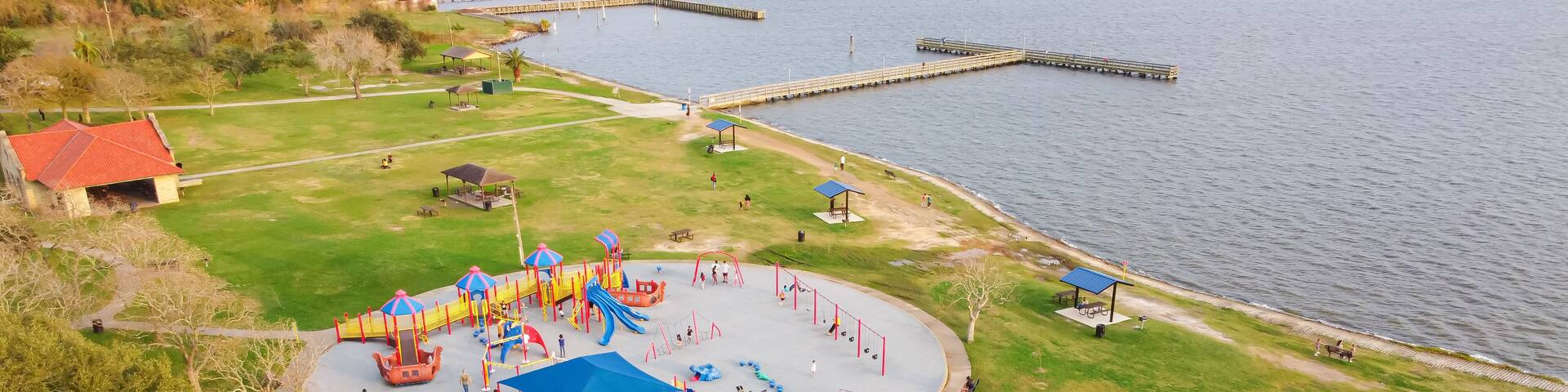 A playground with slides and swings by a lake.