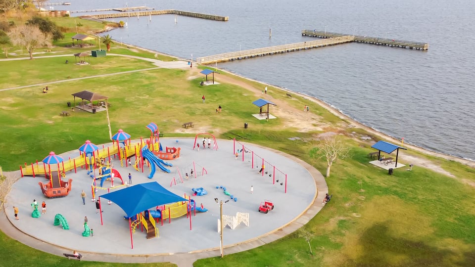 A playground with slides and swings by a lake.