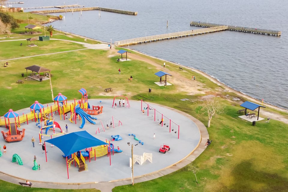 A playground with slides and swings by a lake.