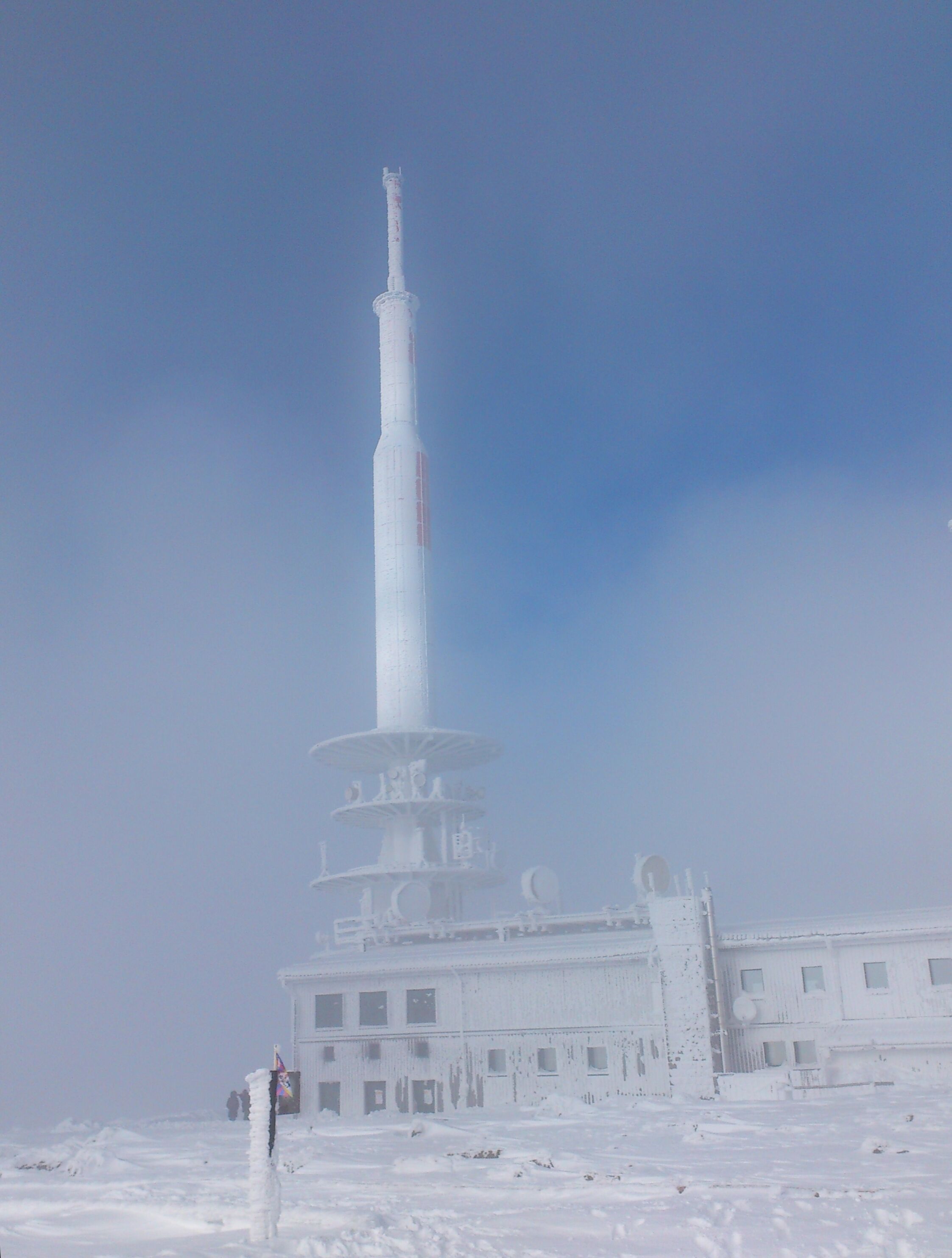 A tall, cylindrical tower with a spiral staircase, surrounded by a snow-covered building.