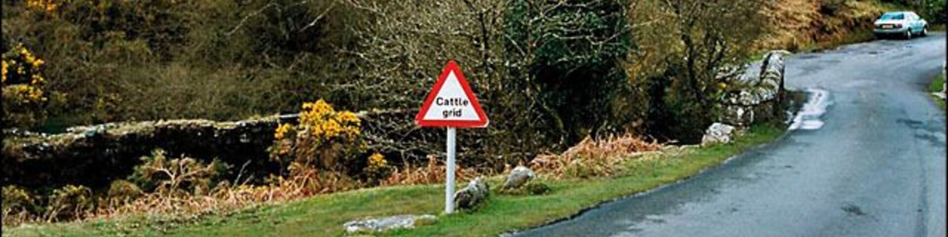 Saddle Bridge, Dartmoor. This scene shows the lane between Venford and Hexworthy, near to the bottom of the hill as it passes over Saddle Bridge. The cattle grid indicates a land boundary is coming up. This is just out of sight, beyond the green car at the bottom of the hill. To the left of the bridge, the foundations for an old stone building are still clearly evident, but I'm not sure what this would have been.