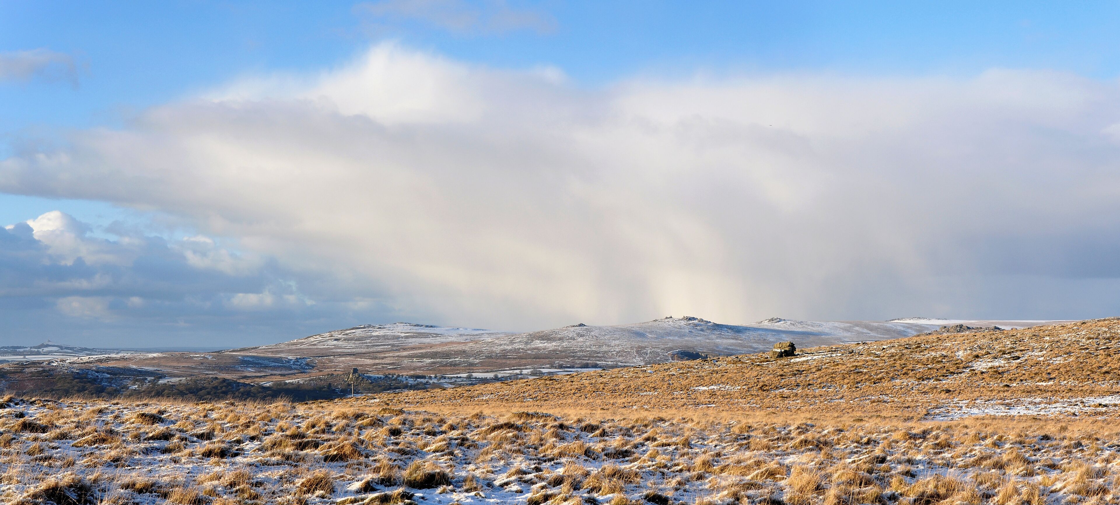 A snowy landscape with a hill and a vehicle in the distance.