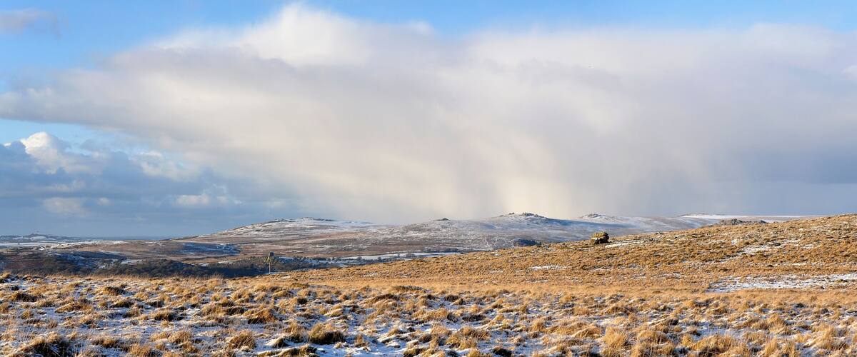 A snowy landscape with a hill and a vehicle in the distance.