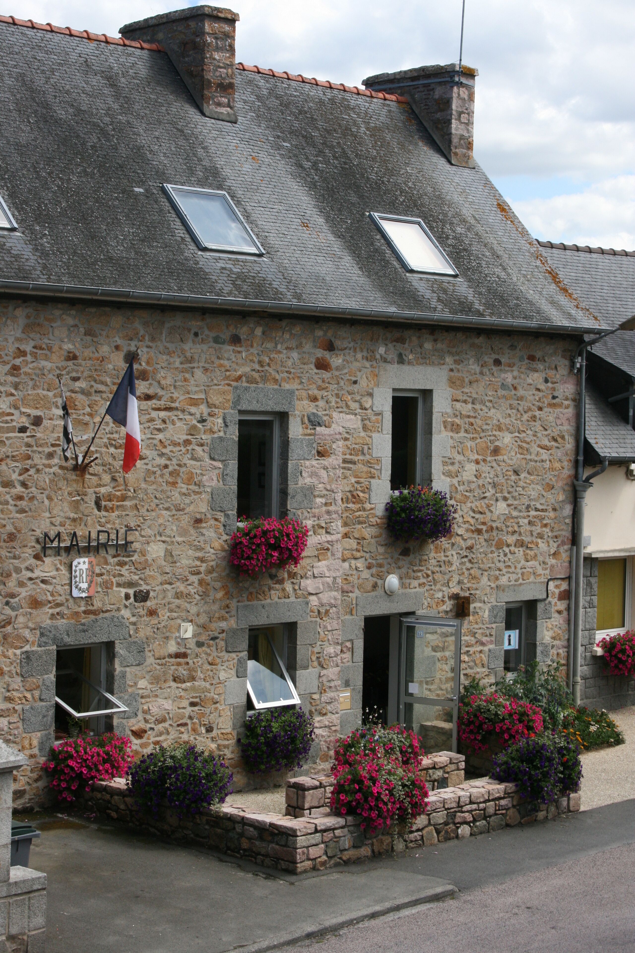 A stone building with a French flag, flower boxes, and the name "MAIRIE" on the wall.