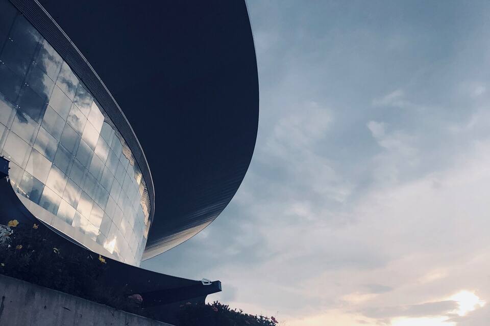 A modern building with a curved glass facade reflecting the sky.