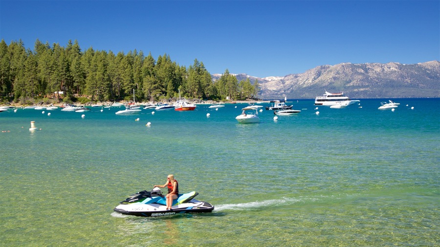 A clear lake with several boats and a jet ski in the foreground.