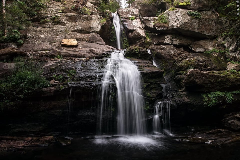 A waterfall cascading over rocks in a forested area.
