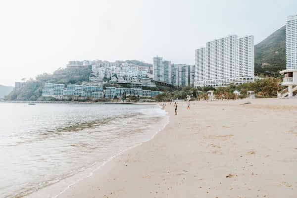 A beach with people, a sandy shore, and high-rise buildings in the background.