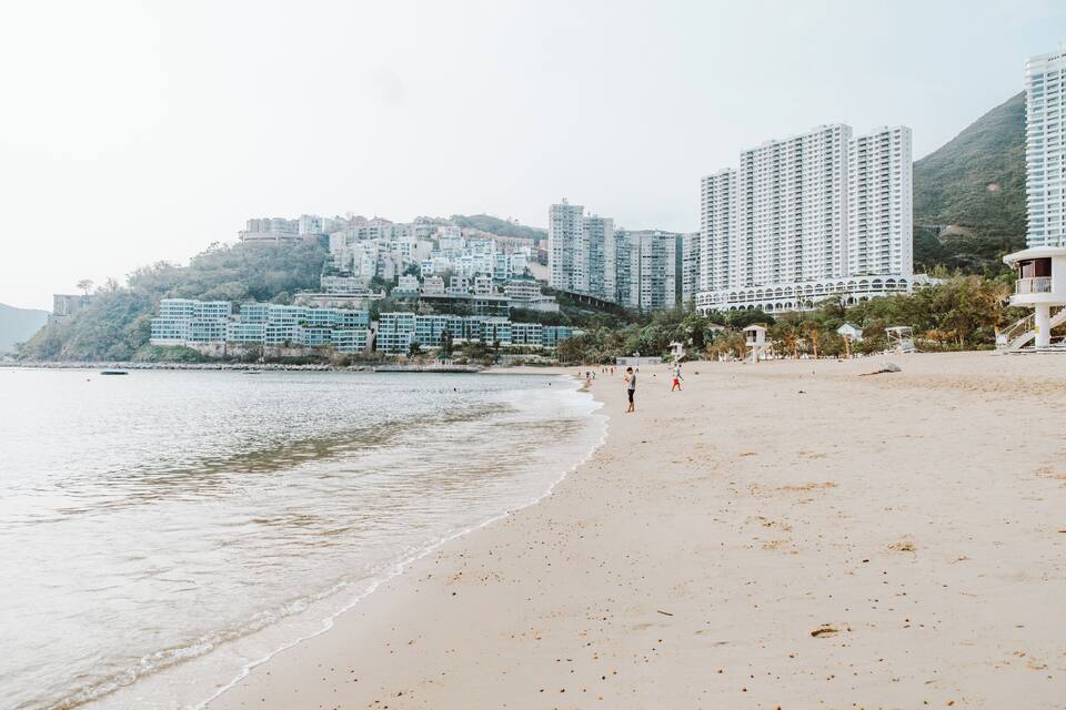 A beach with people, a sandy shore, and high-rise buildings in the background.