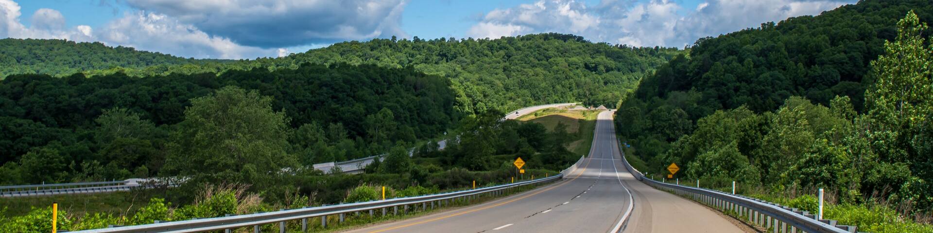 A rural highway in the woods in Franklin, Pennsylvania, USA on a sunny spring day