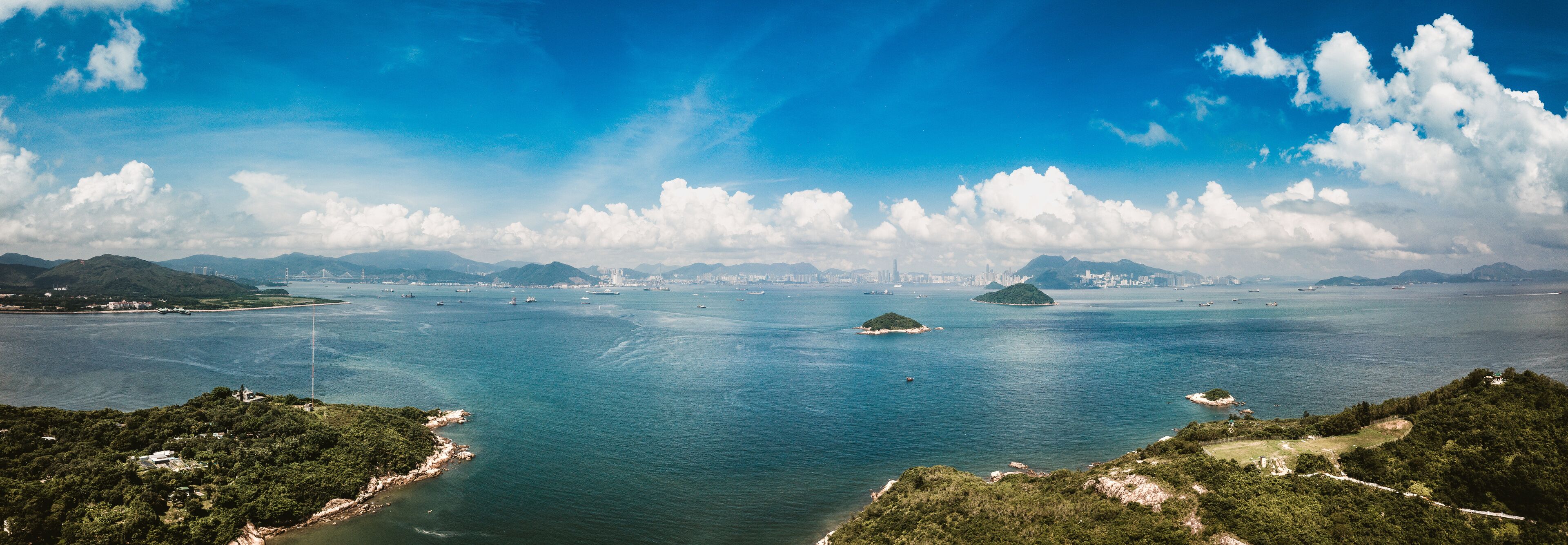 A coastal landscape with a large body of water, several islands, and distant city skyline.