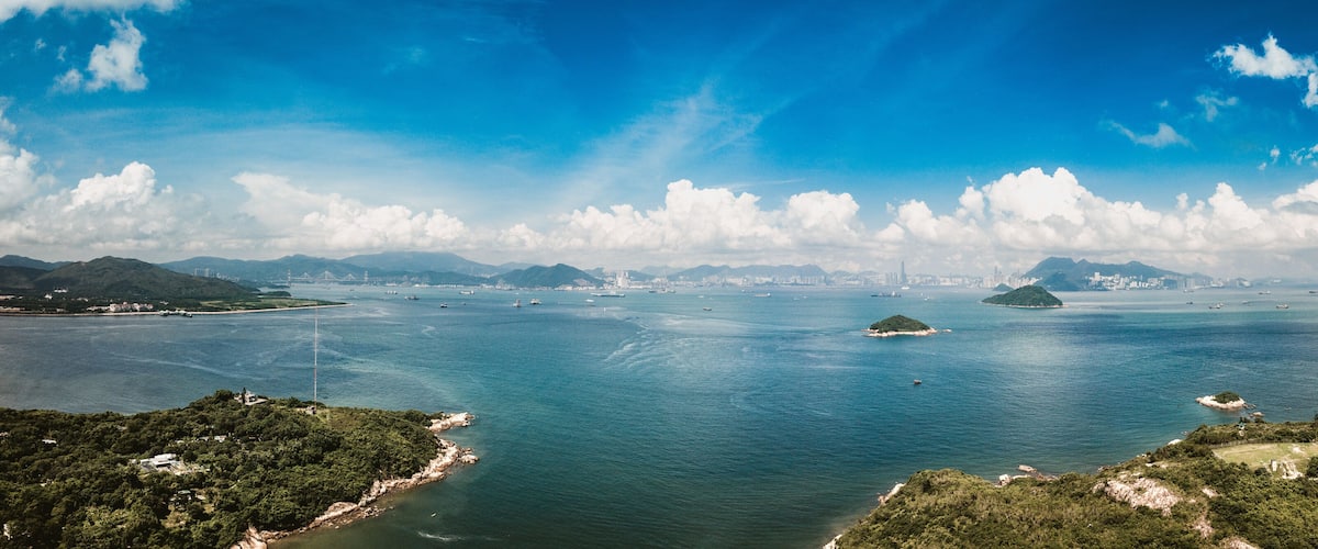 A coastal landscape with a large body of water, several islands, and distant city skyline.