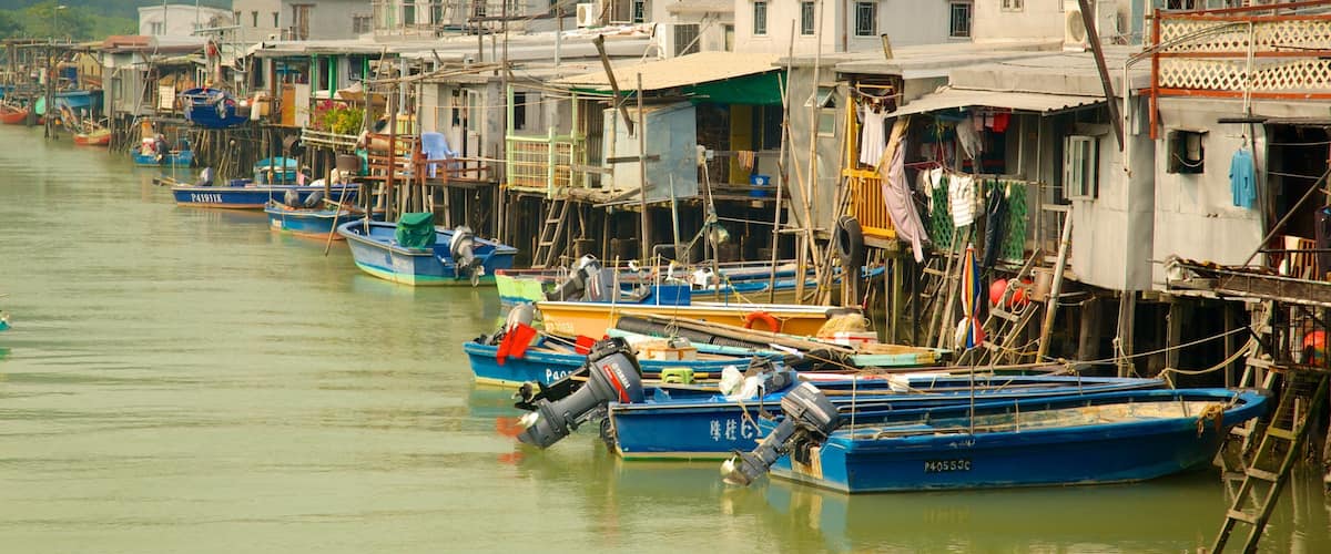 Un hilera de casas de madera tradicionales junto a un río, con barcos amarrados al frente.