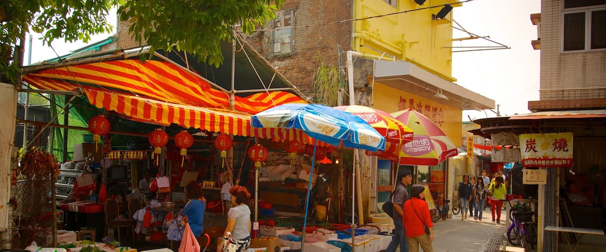 A bustling street market with colorful umbrellas, stalls selling fresh produce, and people walking by.