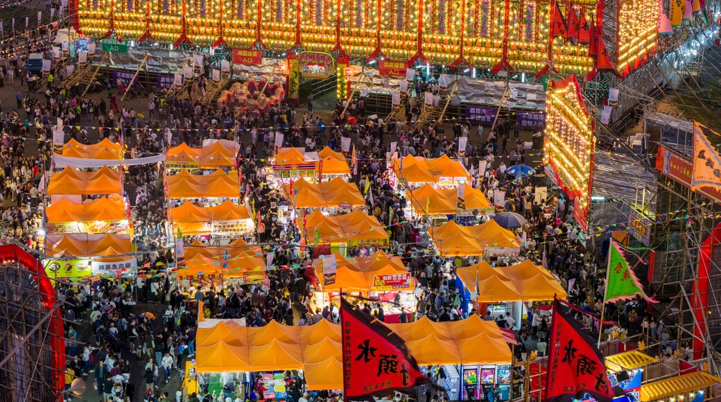 A crowded outdoor market with bright lights and orange tents.