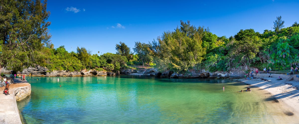 A clear turquoise pool surrounded by lush greenery and rocky outcrops.