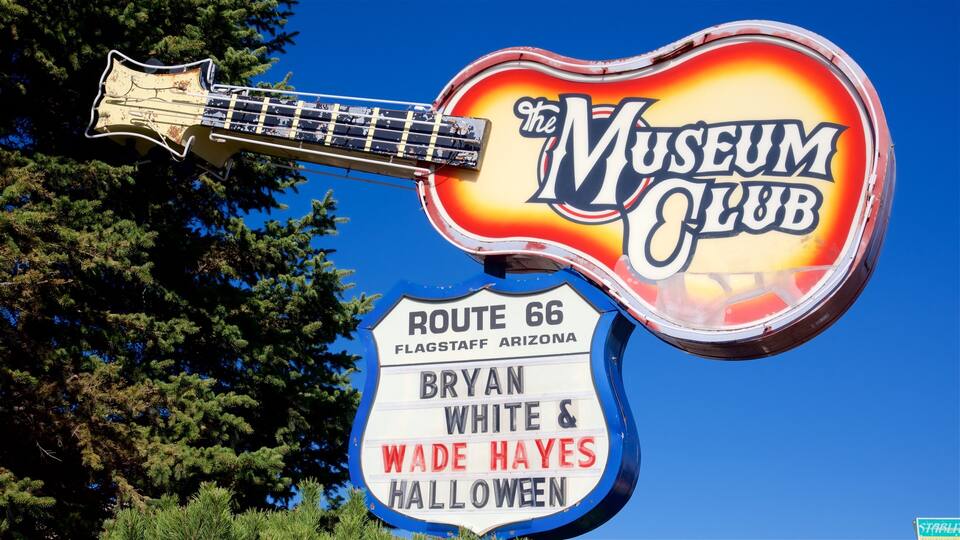 A guitar-shaped sign for The Museum Club with Route 66 directions.