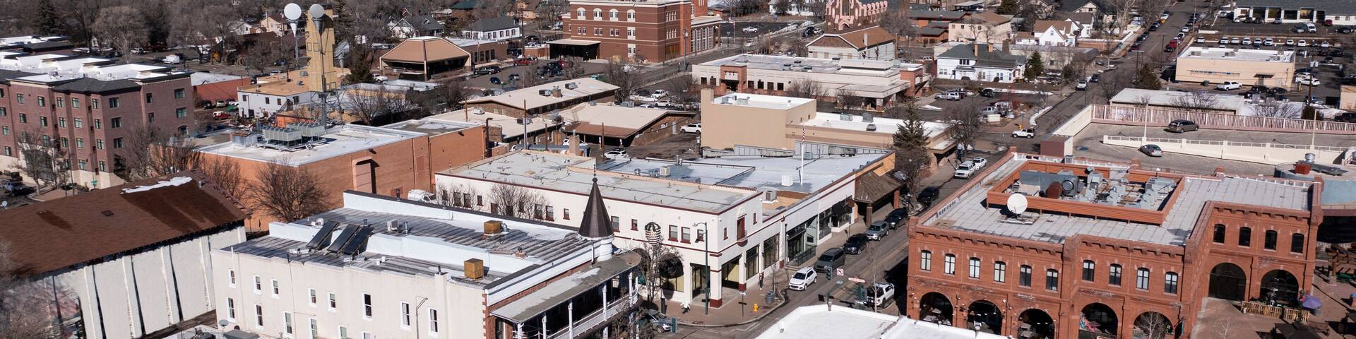 A town with historic buildings, a church, and snow-capped mountains in the background.