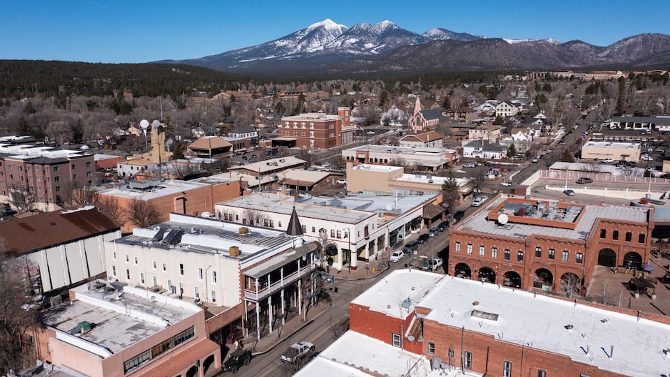 A town with historic buildings, a church, and snow-capped mountains in the background.