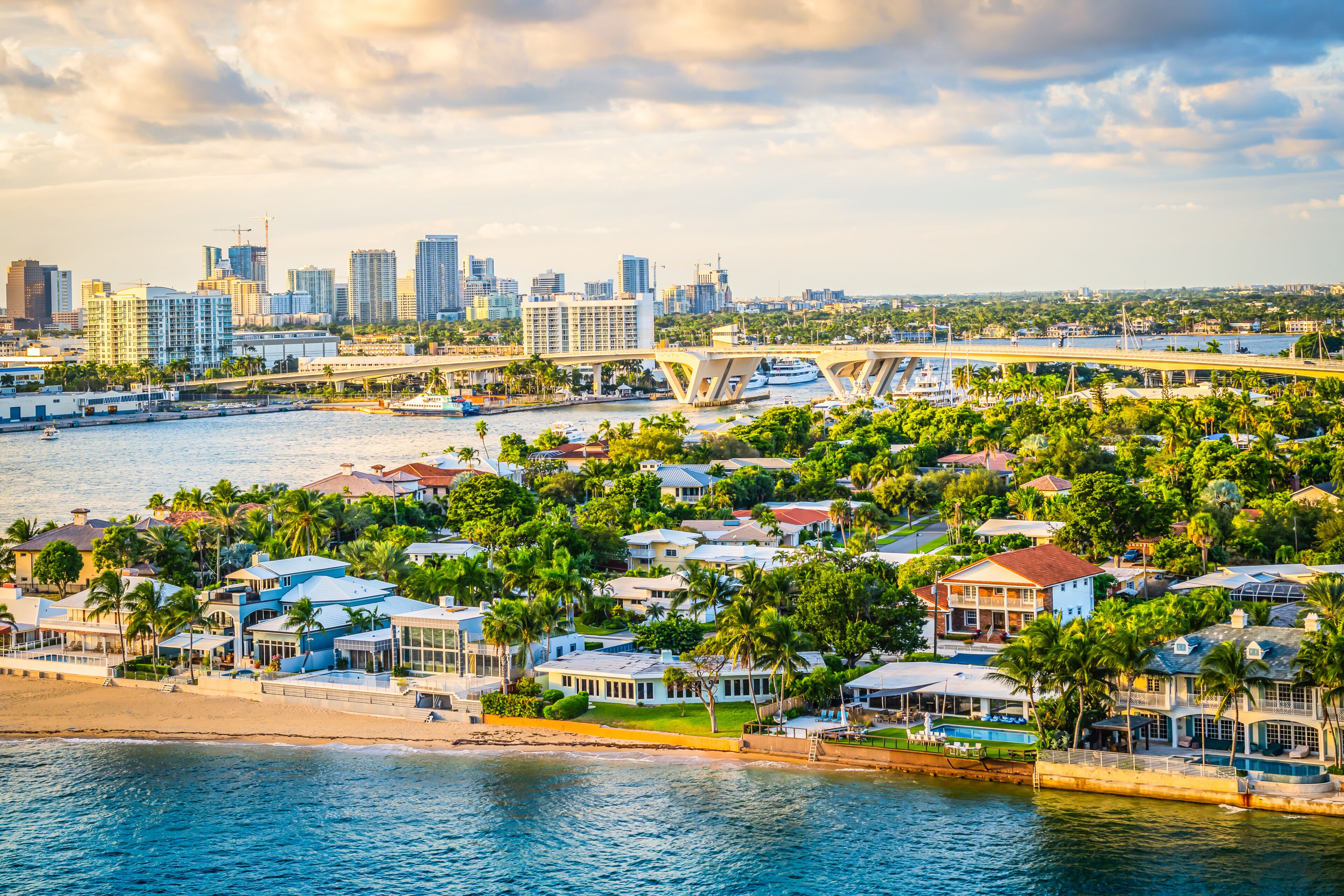 A coastal cityscape with a marina, residential buildings, and a bridge.