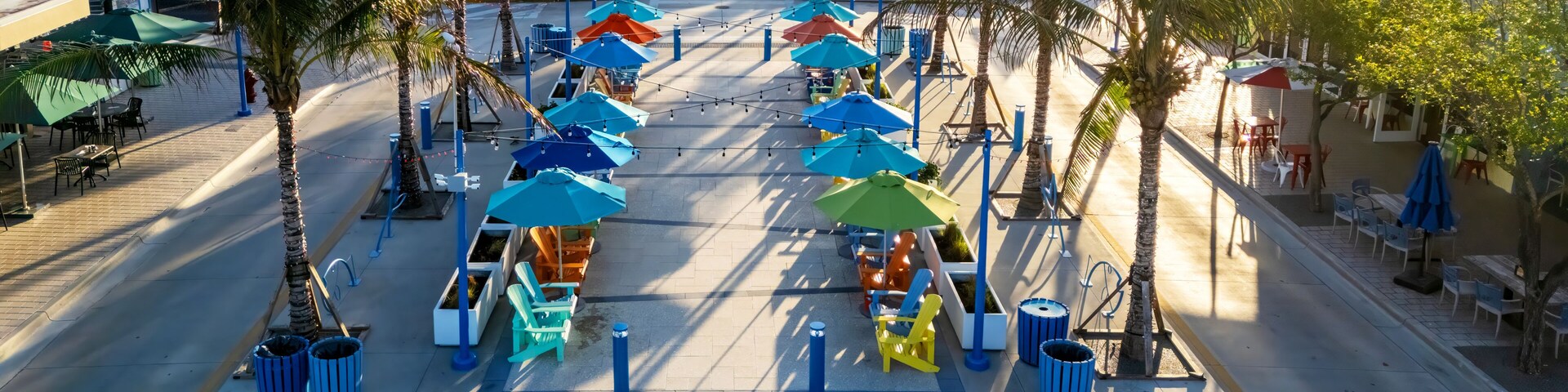 Un paseo marítimo en la playa con sombrillas coloridas, sillas y palmeras.